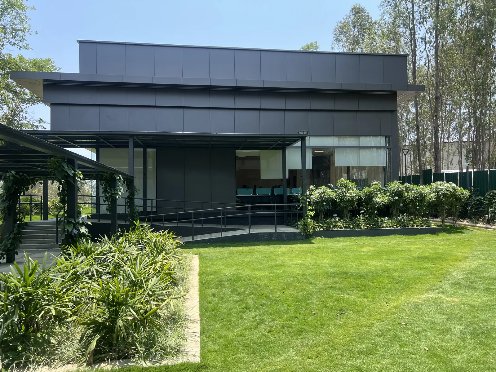 Featured Image of Godrej Vanantara Experience Centre modern black-clad building exterior with covered walkway and lawn at the project site, Hommadevanahalli