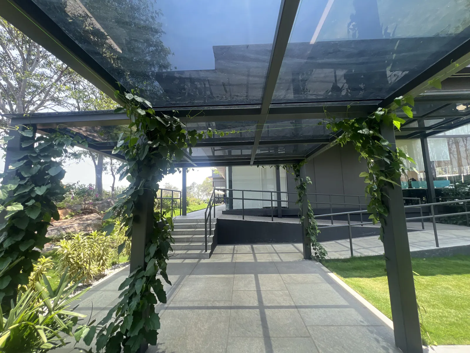 Featured Image of Godrej Vanantara Experience Centre glass-roof pergola walkway with creeper-vine landscaping