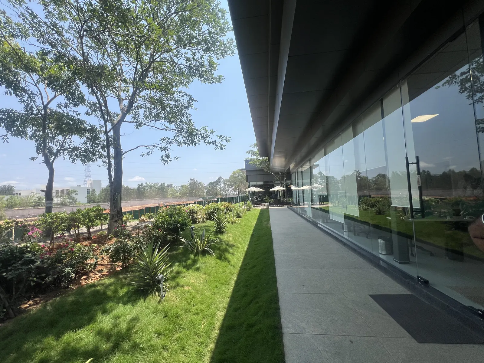 Featured Image of Godrej Vanantara Experience Centre outdoor side walkway beside the glass facade with outdoor cafe view