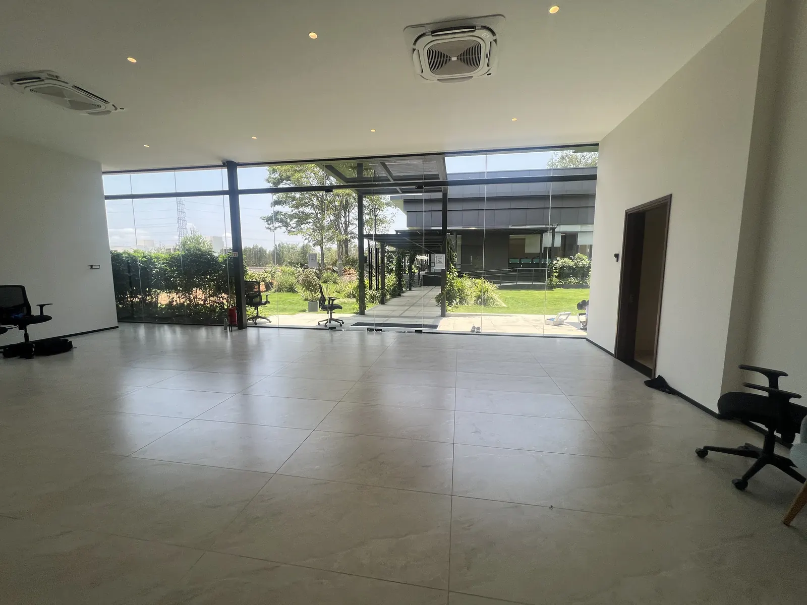 Featured Image of Godrej Vanantara Experience Centre sales lounge interior with full-height glass facade and landscaped courtyard view